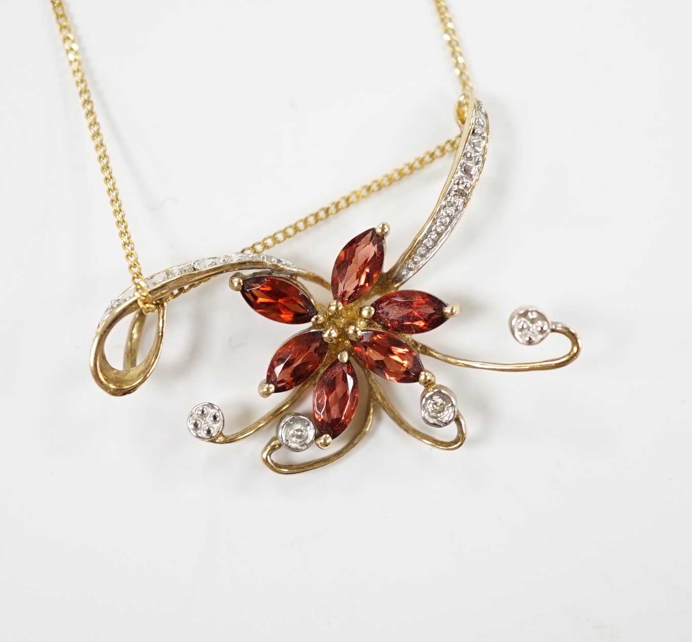 A modern 9ct gold and gem set foliate pendant on chain, pendant 30mm, gross weight 2.6 grams.